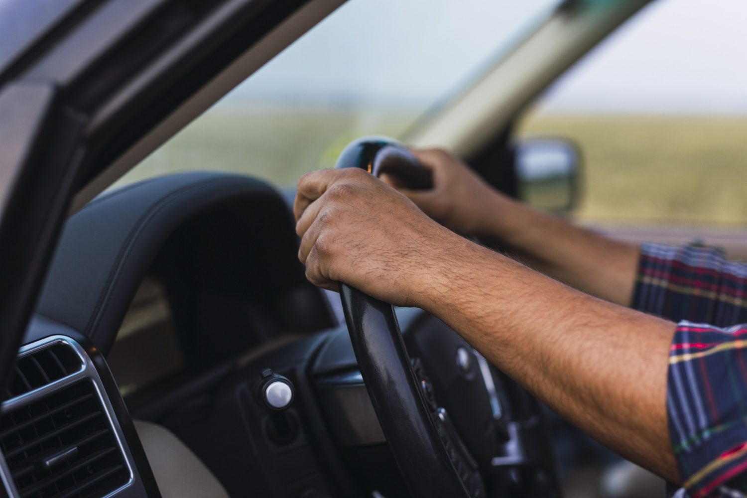 closeup-shot-hands-person-steering-wheel-modern-car